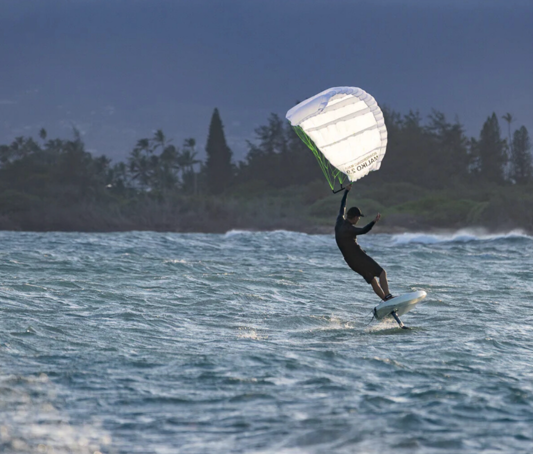 BRM parawing rider backlit at sunset in Maui with palm trees on the shoreline