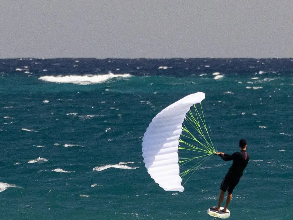 BRM Paia rider foiling in turquoise Hawaiian water with white parawing deployed