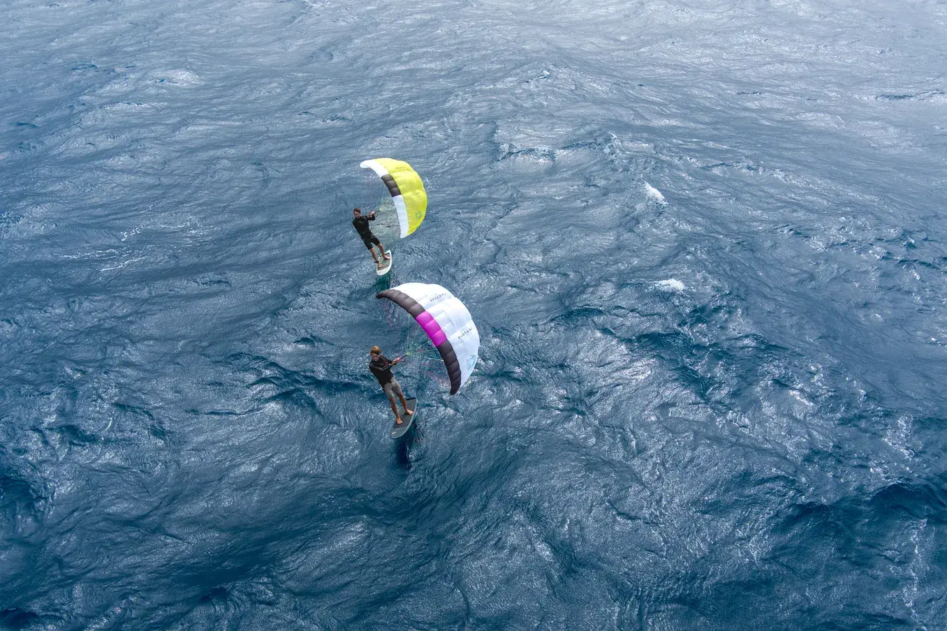 Duotone Stash rider foiling at aerial drone perspective, two riders on deep blue ocean
