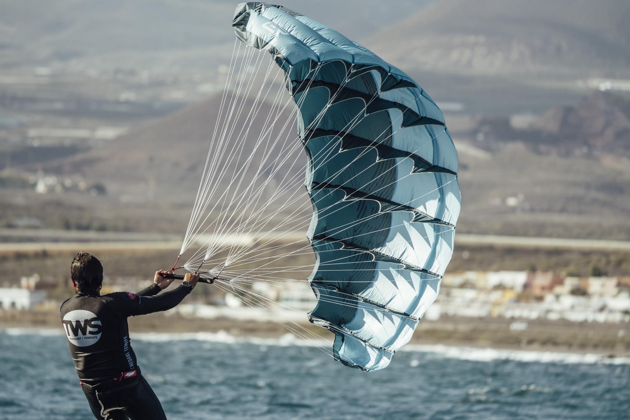 Parawing foiler riding past dramatic volcanic cliffs with an Aeryn P1 wing
