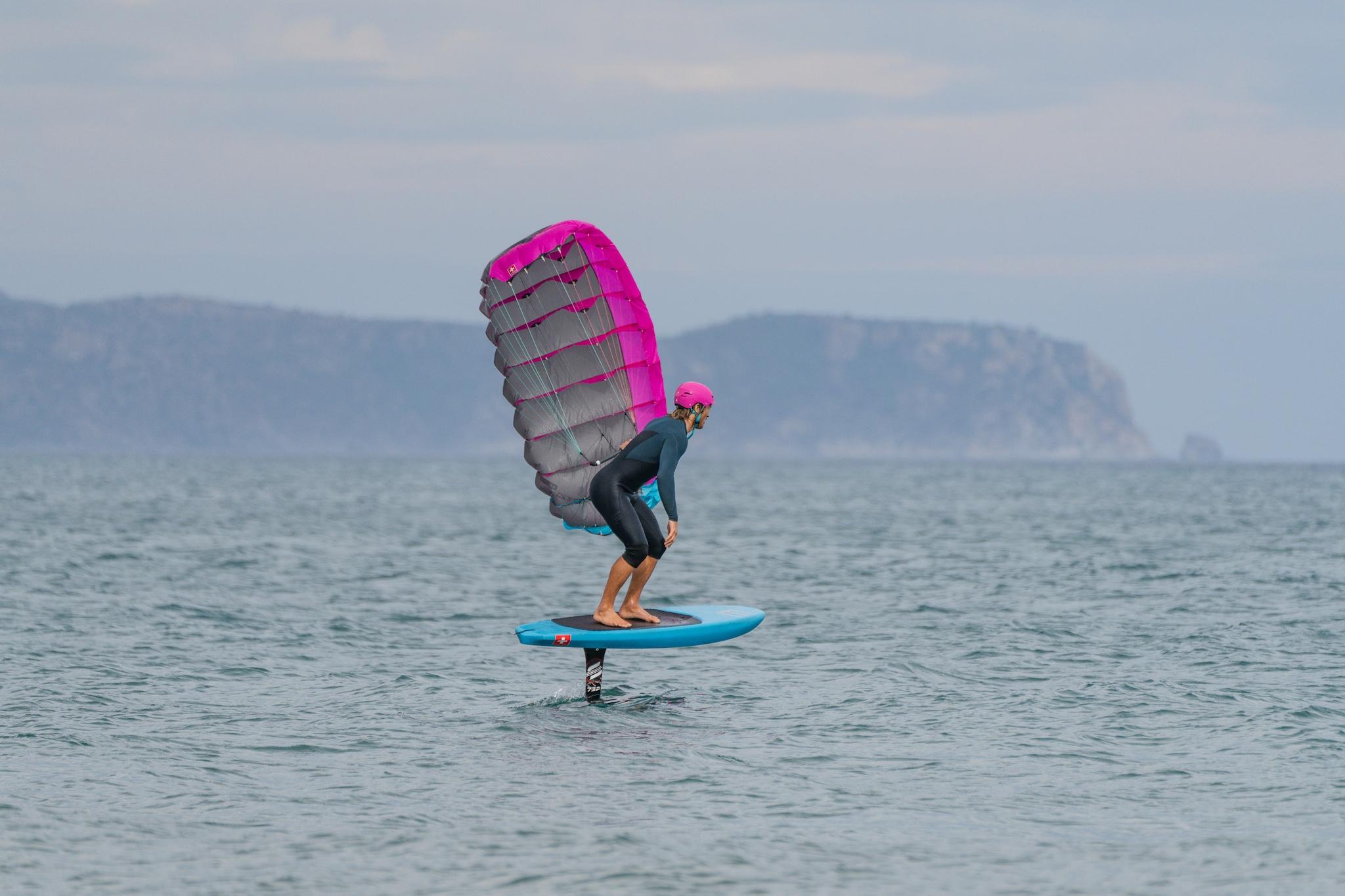 Ensis Roger rider going upwind with parawing overhead and cliffs in the background