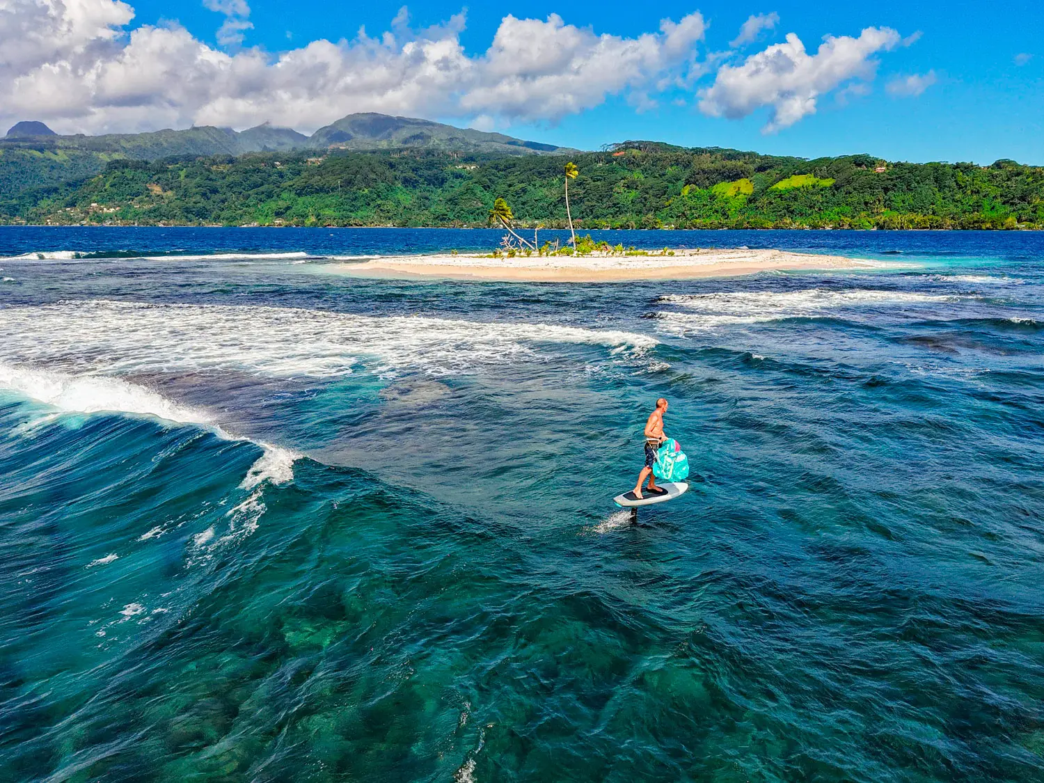 Rider foiling in tropical water with a Gong Lowkite parawing near a palm-fringed island