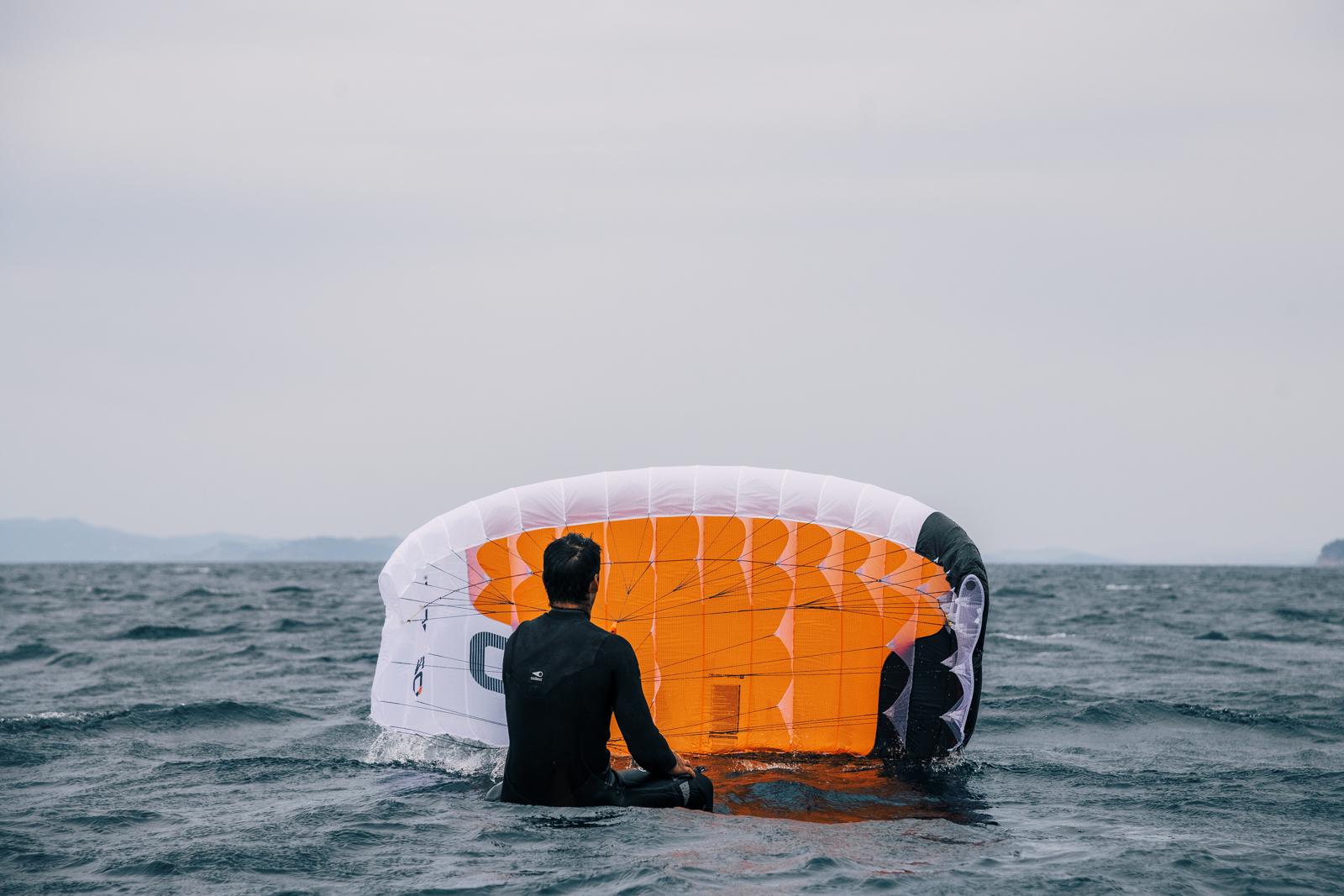 Ozone Pocket Rocket rider preparing for a water start, sitting with wing on the ocean surface