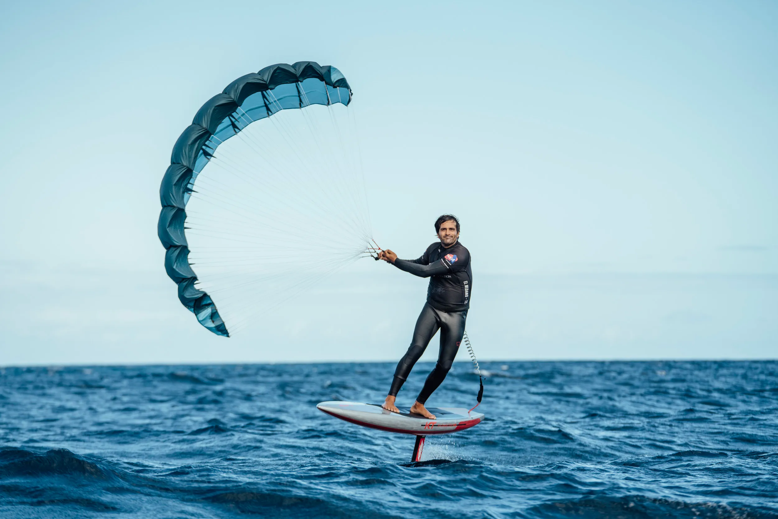 Aeryn P1 rider foiling with wing in low arc, second rider visible in the background on open ocean