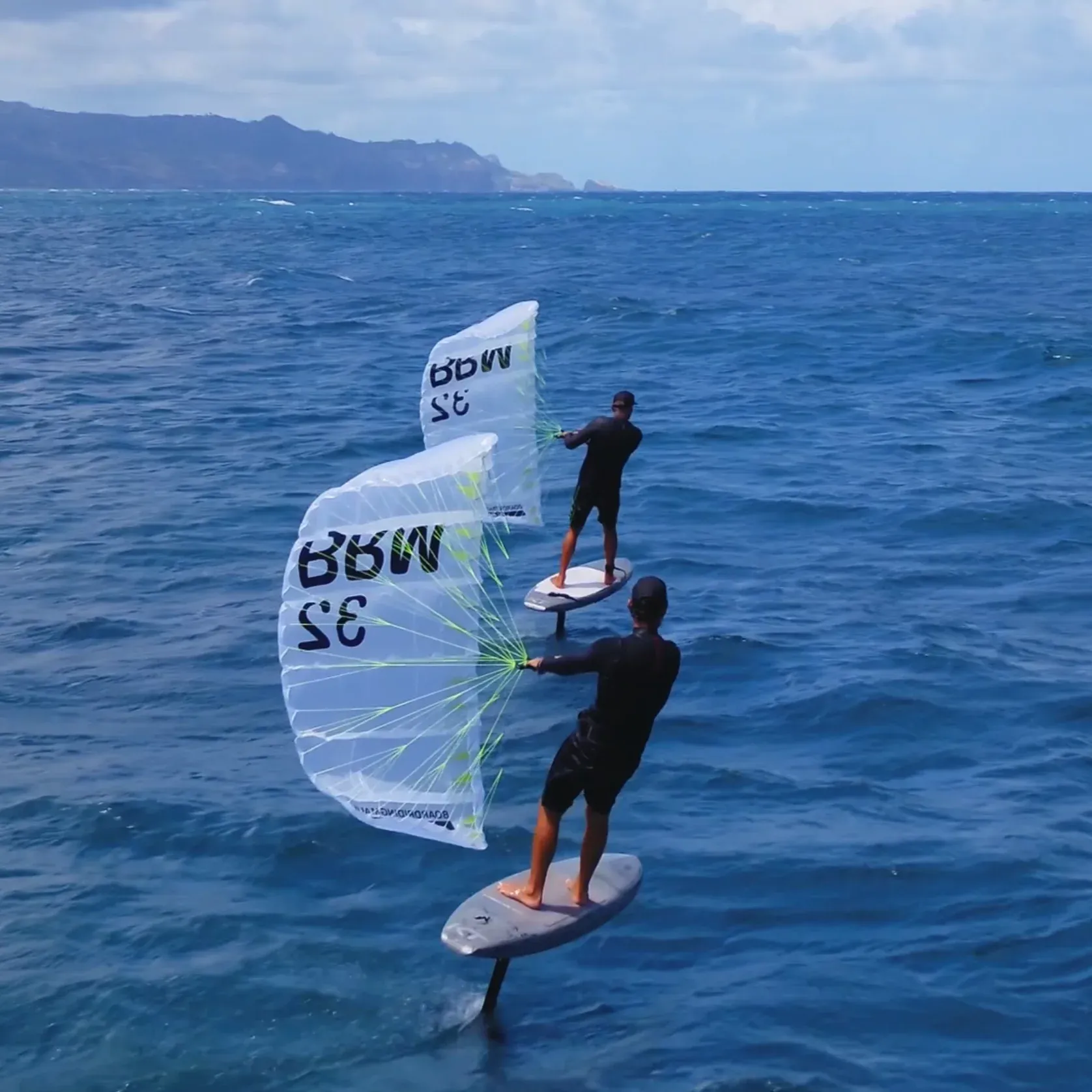 Greg and Scott foiling together on BRM Kanaha parawings, aerial drone view over deep blue Maui ocean