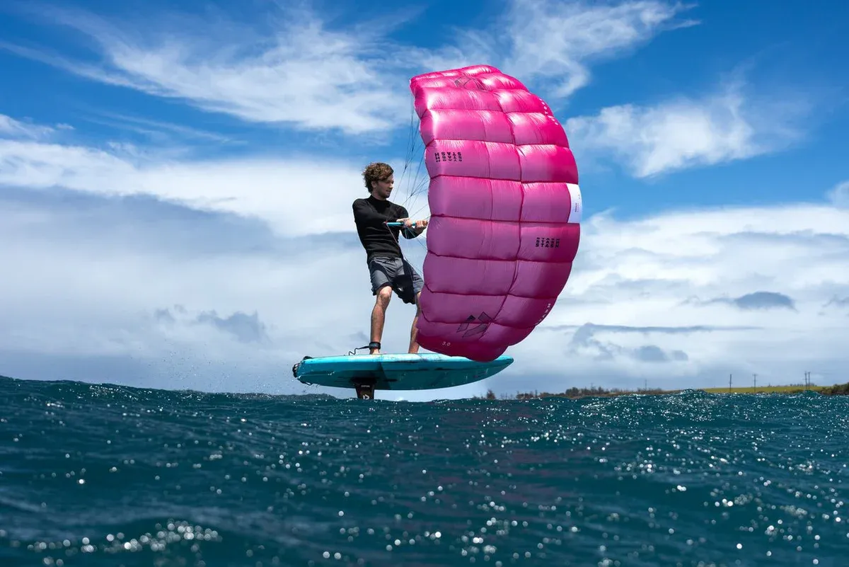 Duotone Stash rider foiling with pink parawing deployed, wide ocean view