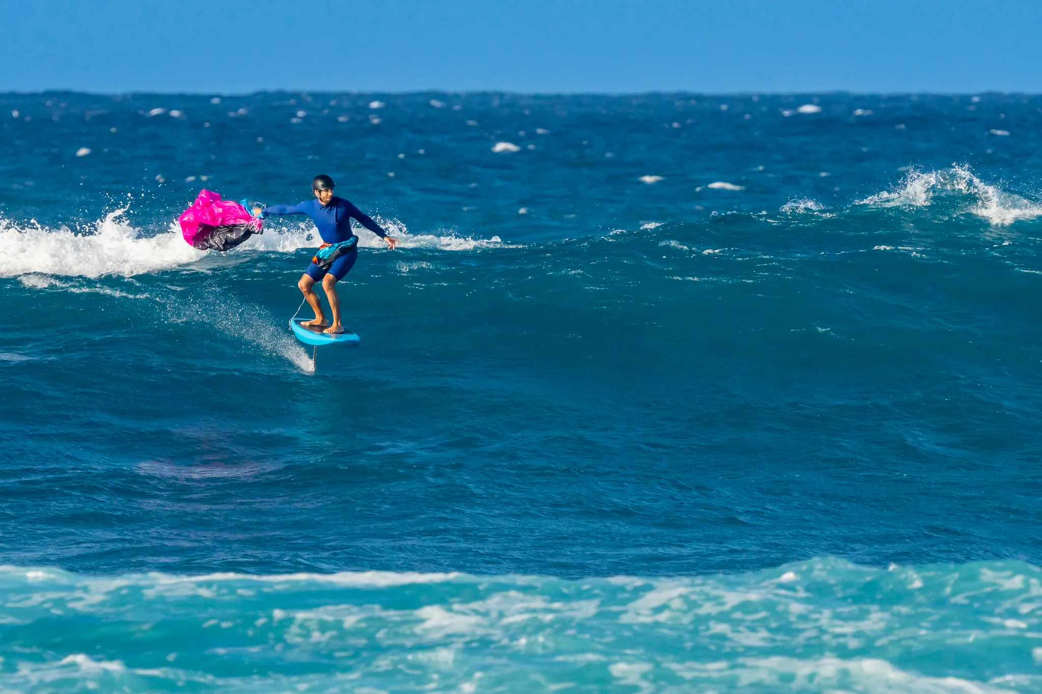 Ensis Roger rider foiling on a wave with the parawing deployed overhead