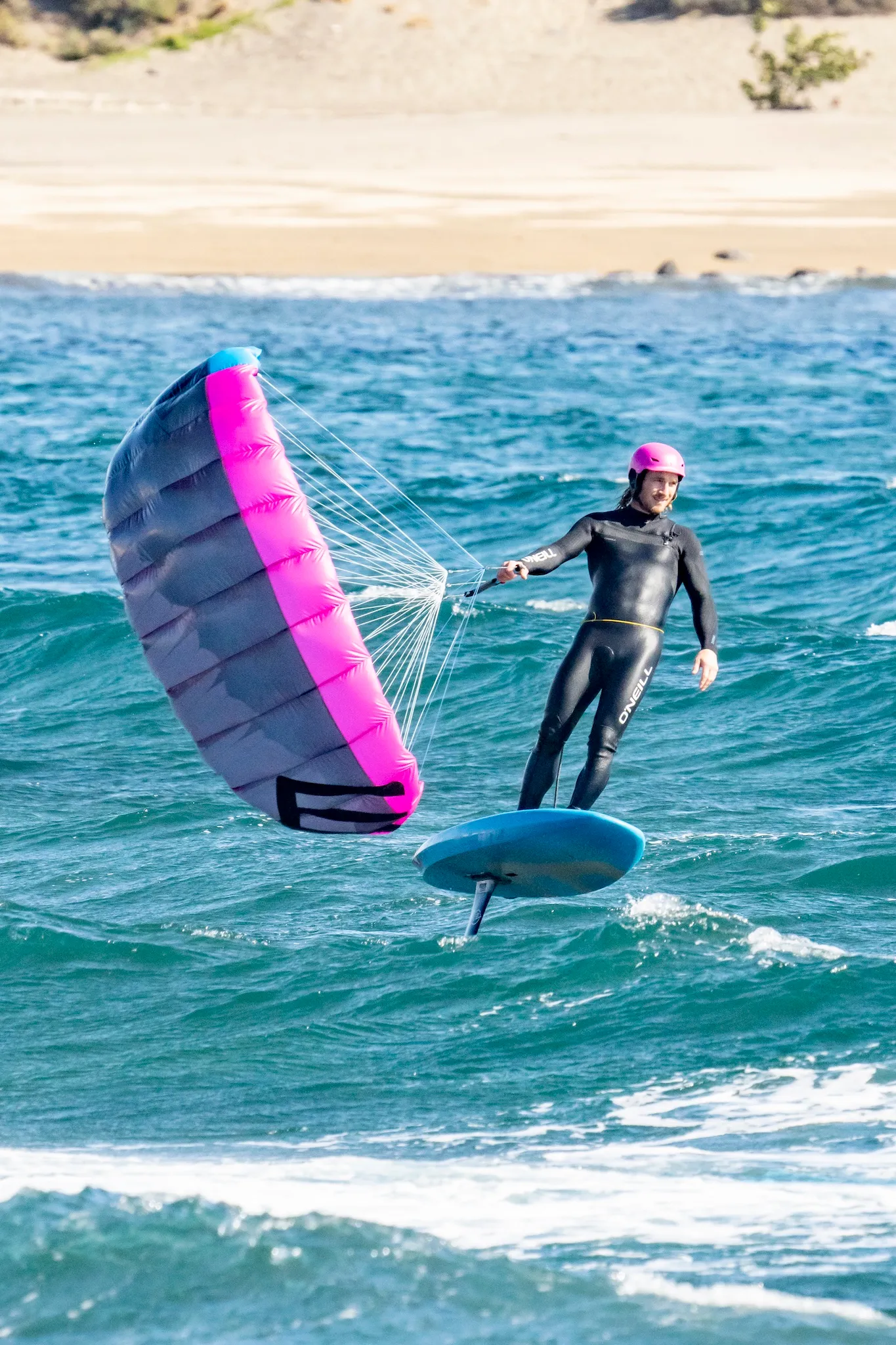 Parawingfoiler heading upwind along a coastal shoreline with wing deployed