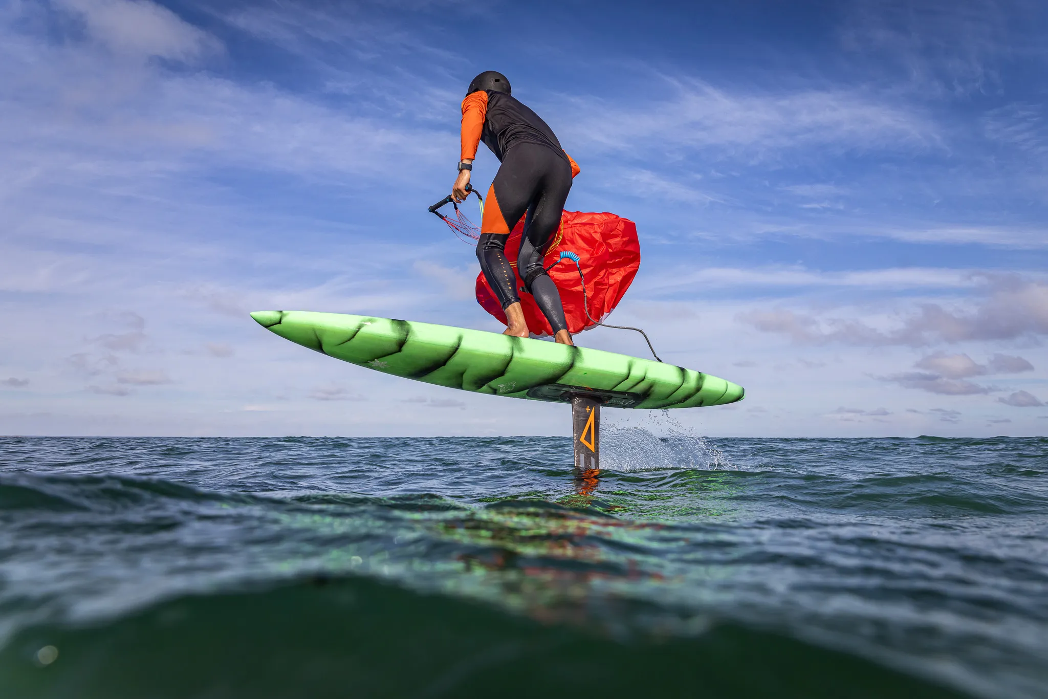 Flow D-Wing rider on foil showing the board and hydrofoil in detail at low angle