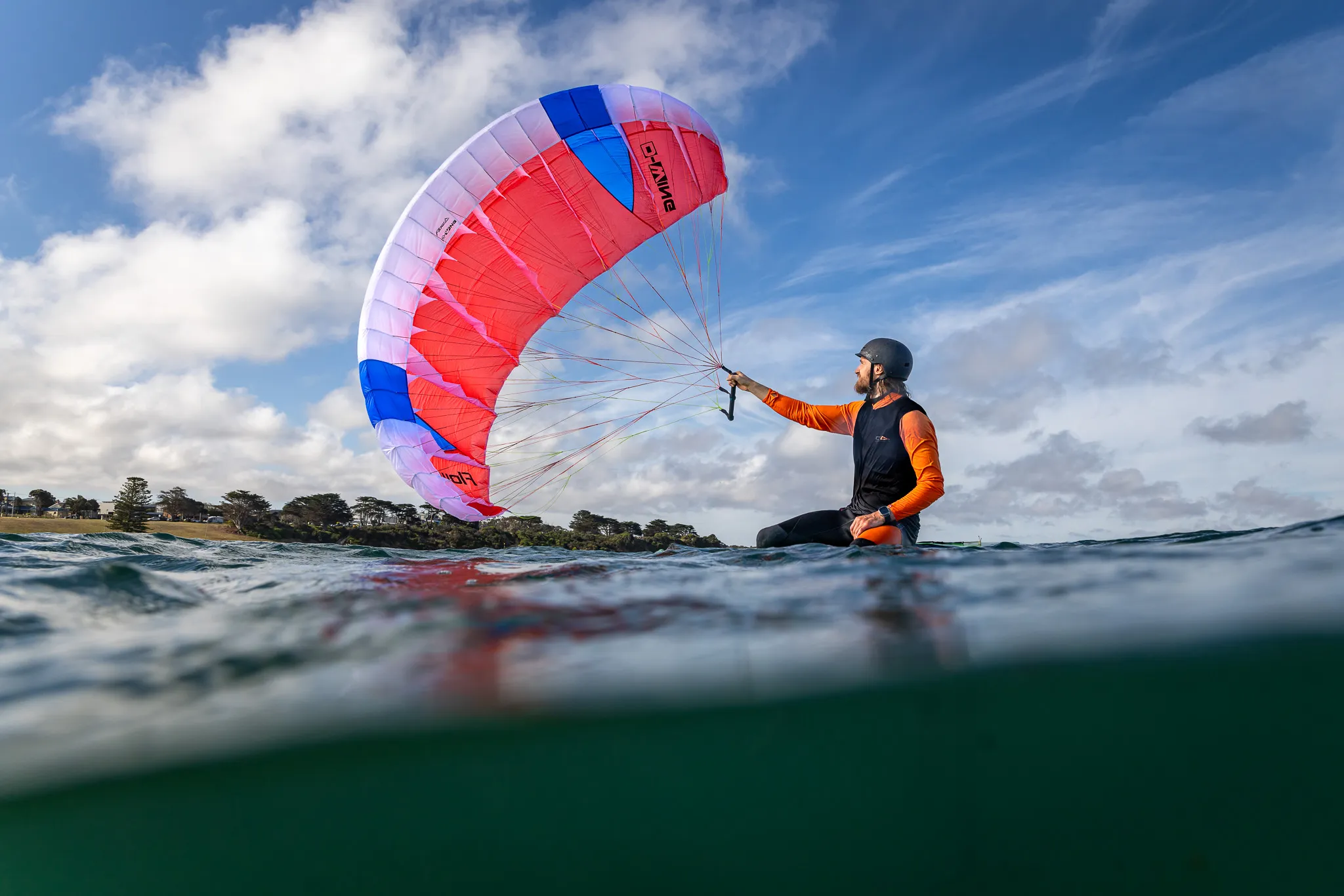 Parawingfoiler sitting on the water with wing fully inflated overhead, preparing to ride