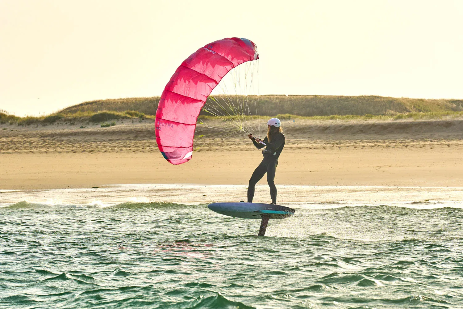 Gong Lowkite rider foiling in golden hour light near sand dunes