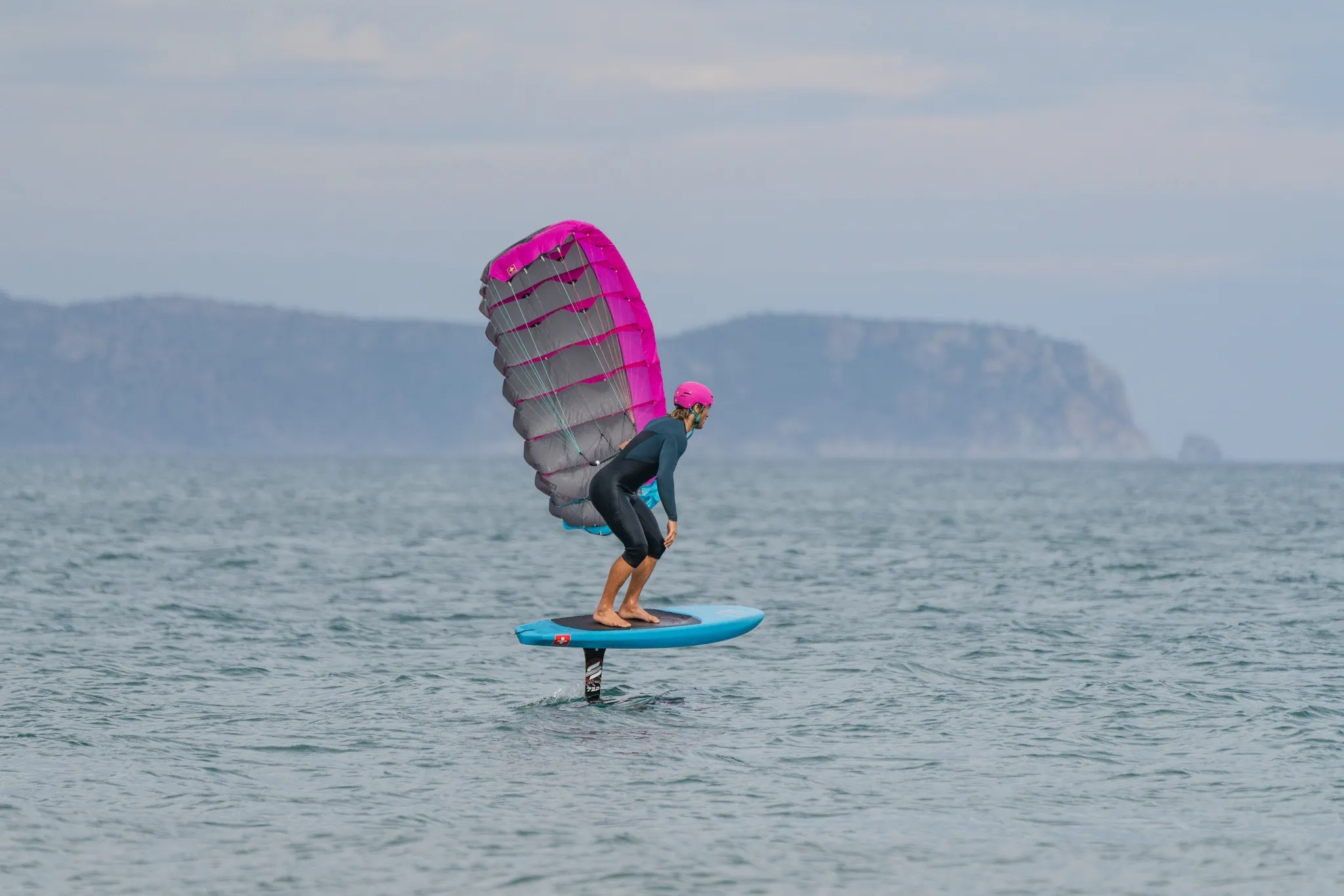 Ensis Roger rider going upwind with parawing overhead and cliffs in the background