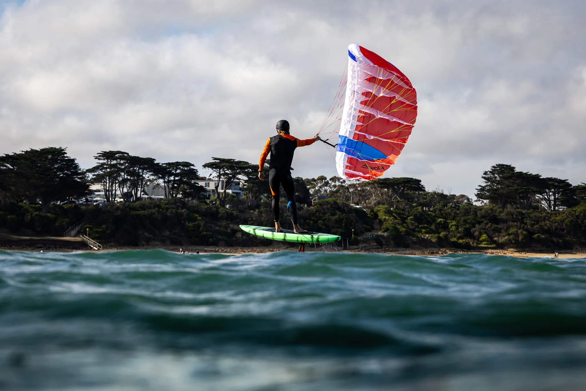 Flow D-Wing rider foiling along the Australian coast with the wing in a clean arc