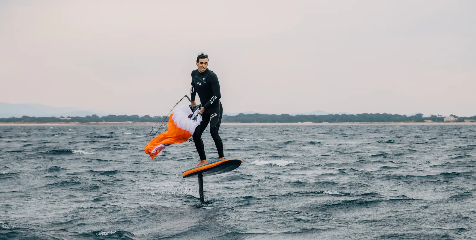 Ozone Pocket Rocket rider smiling while stowing the wing mid-session on the foil